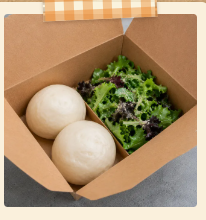 Steamed buns in a kraft box with greens